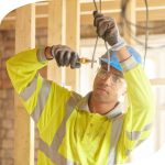 Young electrical apprentice cutting electrical cord on build site.